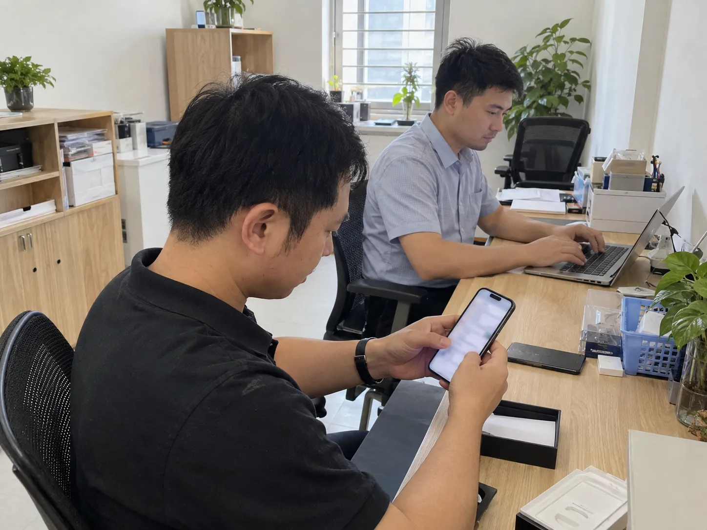 Nhân viên làm việc và kiểm tra điện thoại tại bàn trong văn phòng