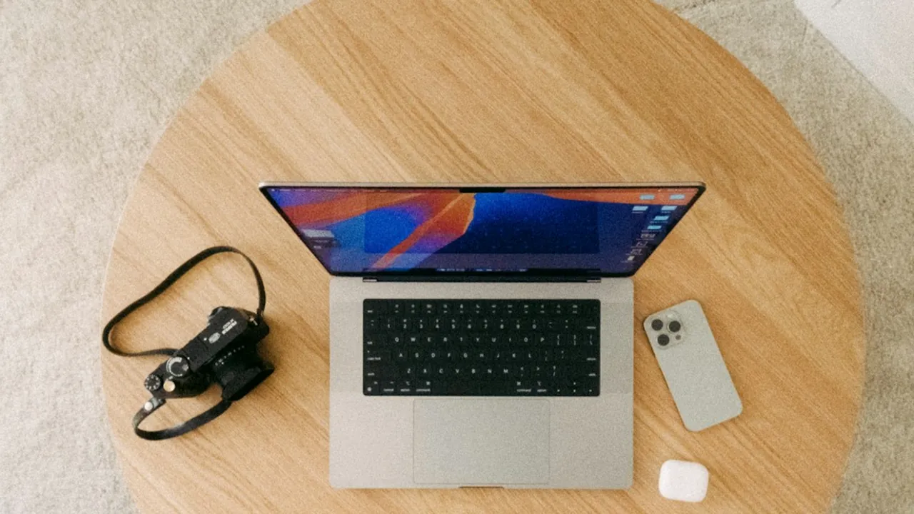 iPhone, laptop và máy ảnh trên bàn gỗ nhìn từ trên xuống